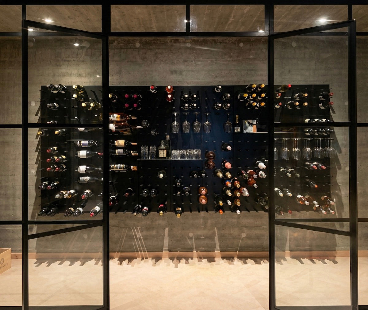Glass wine cellar using STACT Premier BlackOut wine racks with integrated shelves and stemware storage.