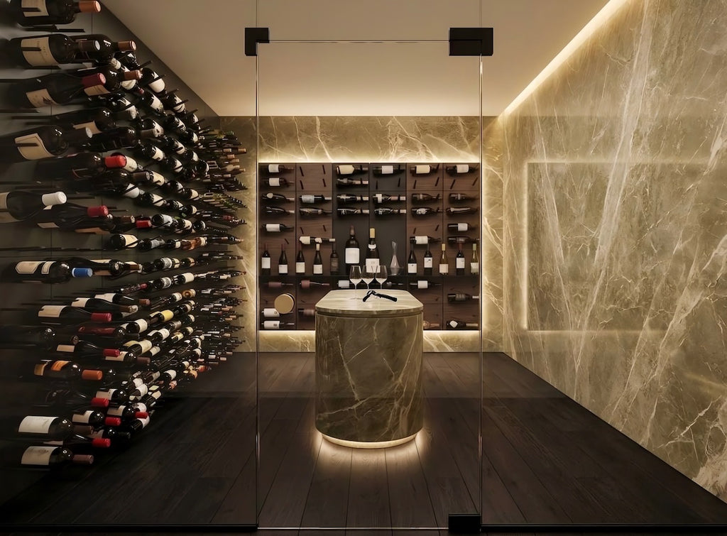 A luxury wine cellar interior featuring a curved wall of wine bottles on the left, a central marble-topped display pedestal, and a back wall of shelving filled with wine bottles. The space has warm ambient lighting, dark wood flooring, and a large beige marble wall on the right.