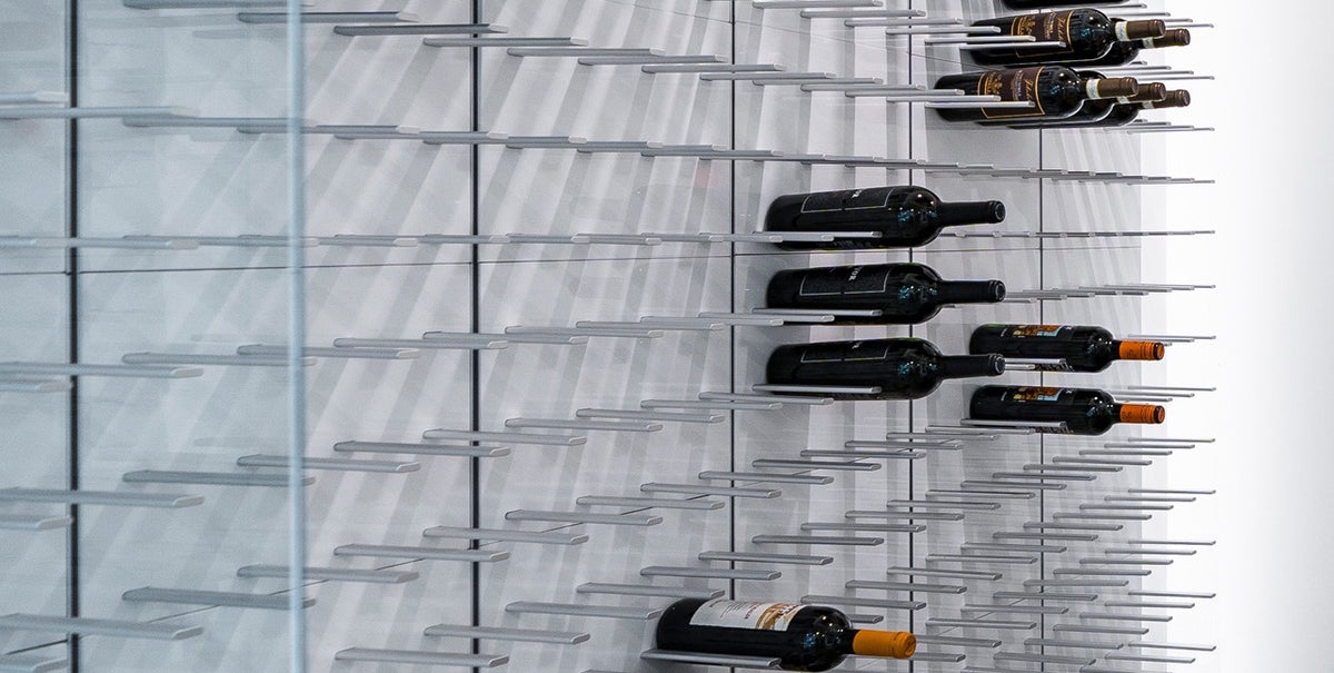 Close-up of STACT Premier White & Silver wall-mounted C-type wine racks in a modern glass wine cellar.