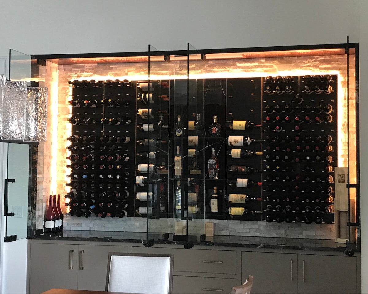 Glass-enclosed dining room wine cellar with STACT Premier Black & Gold label-forward storage.