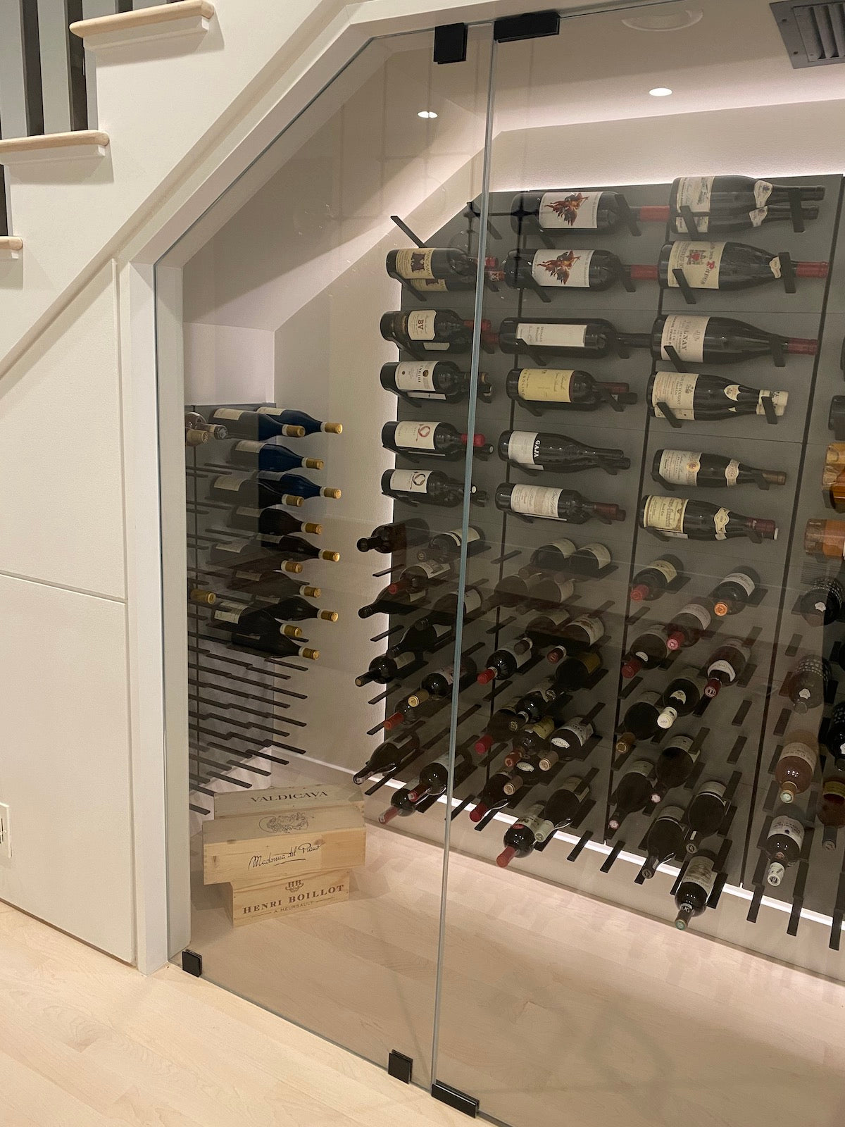 Wine cellar under the stairs with STACT Premier Concrete & Black wall-mounted wine storage.